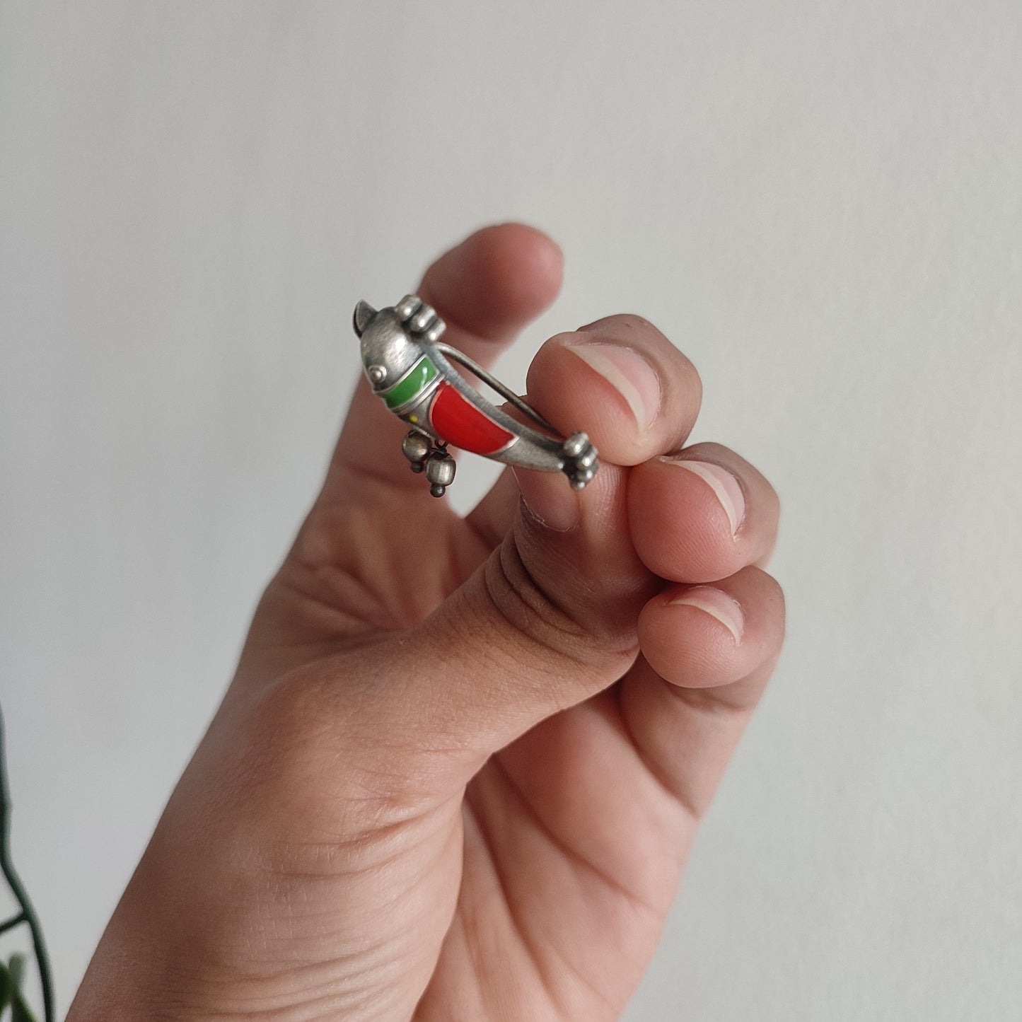 Hand holding a small metallic object against a plain background