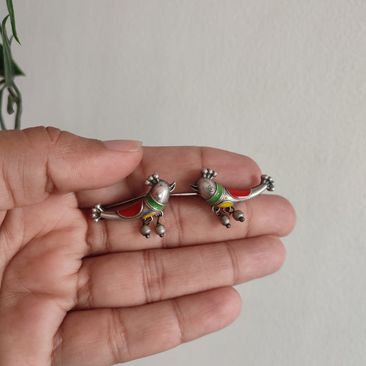 Two small decorative figurines held in a hand against a plain background