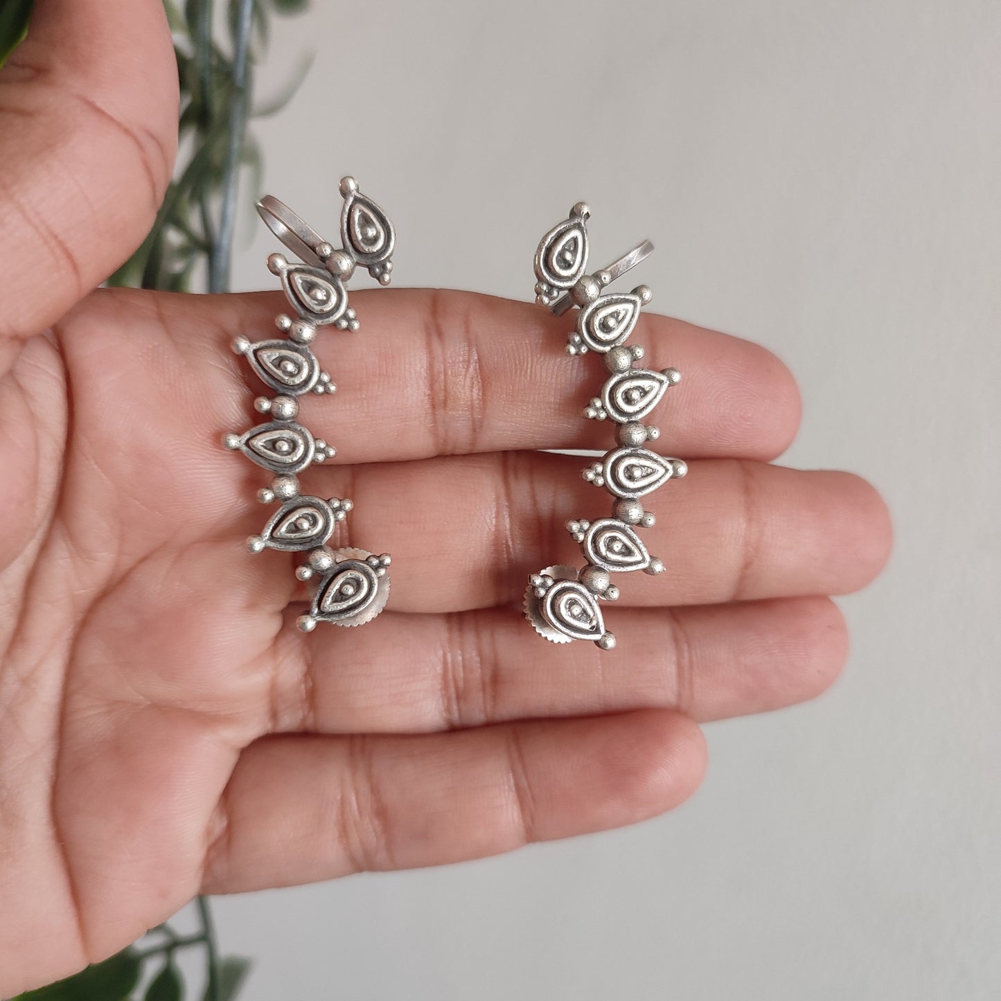 Silver rings on a hand with a blurred green plant background