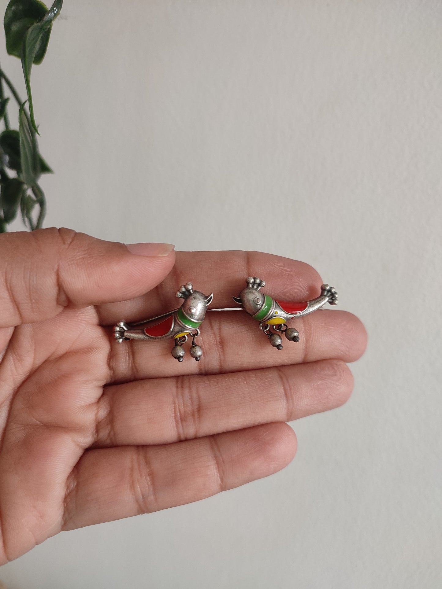 Belly button ring with cartoon character design held in a hand against a neutral background