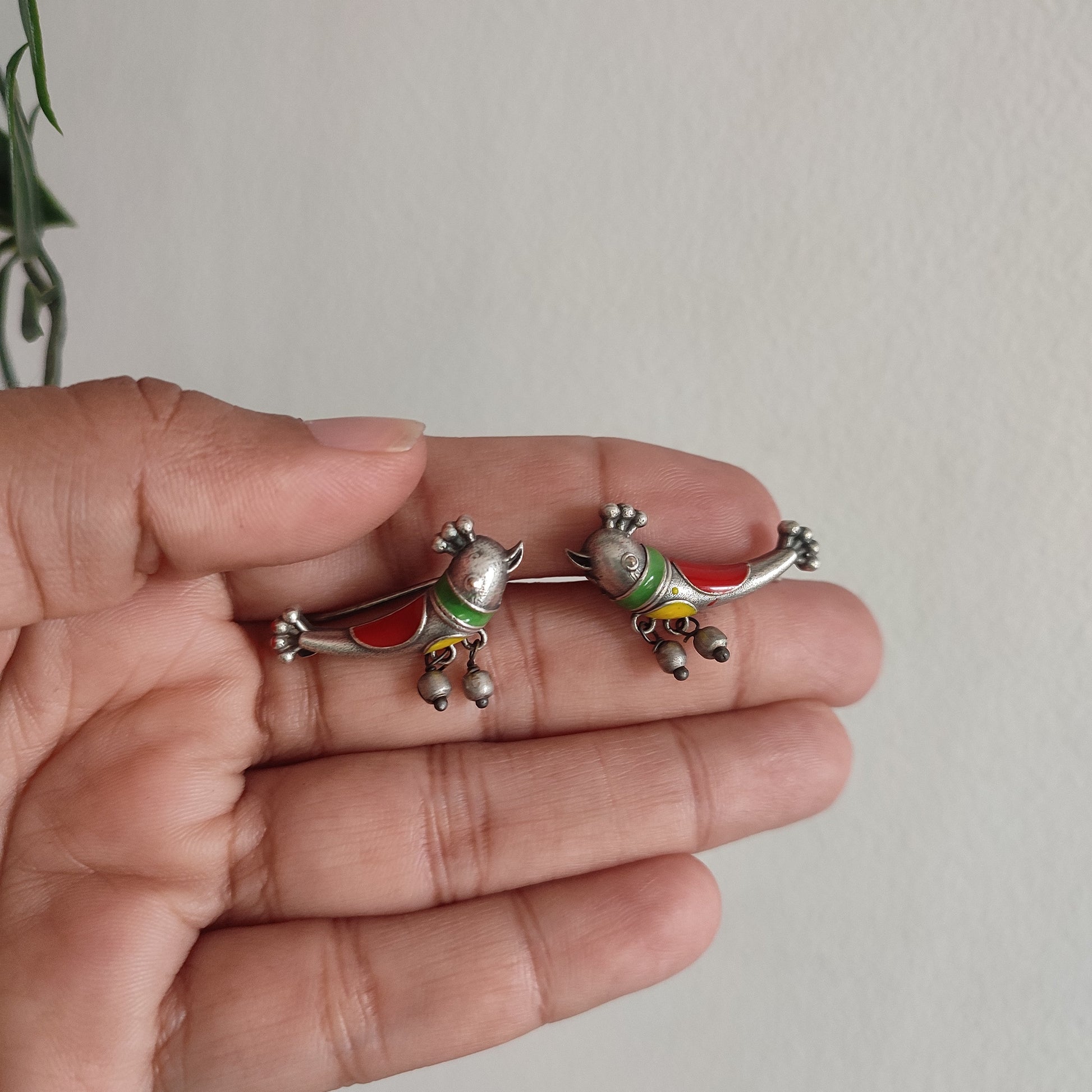Two small decorative figurines held in a hand against a plain background