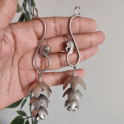 Silver earrings held in a hand with a blurred background