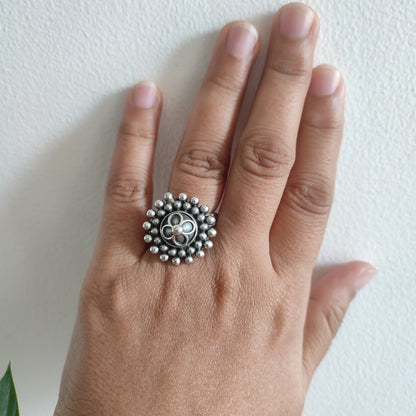 Hand wearing a silver ring with a decorative design on a white background