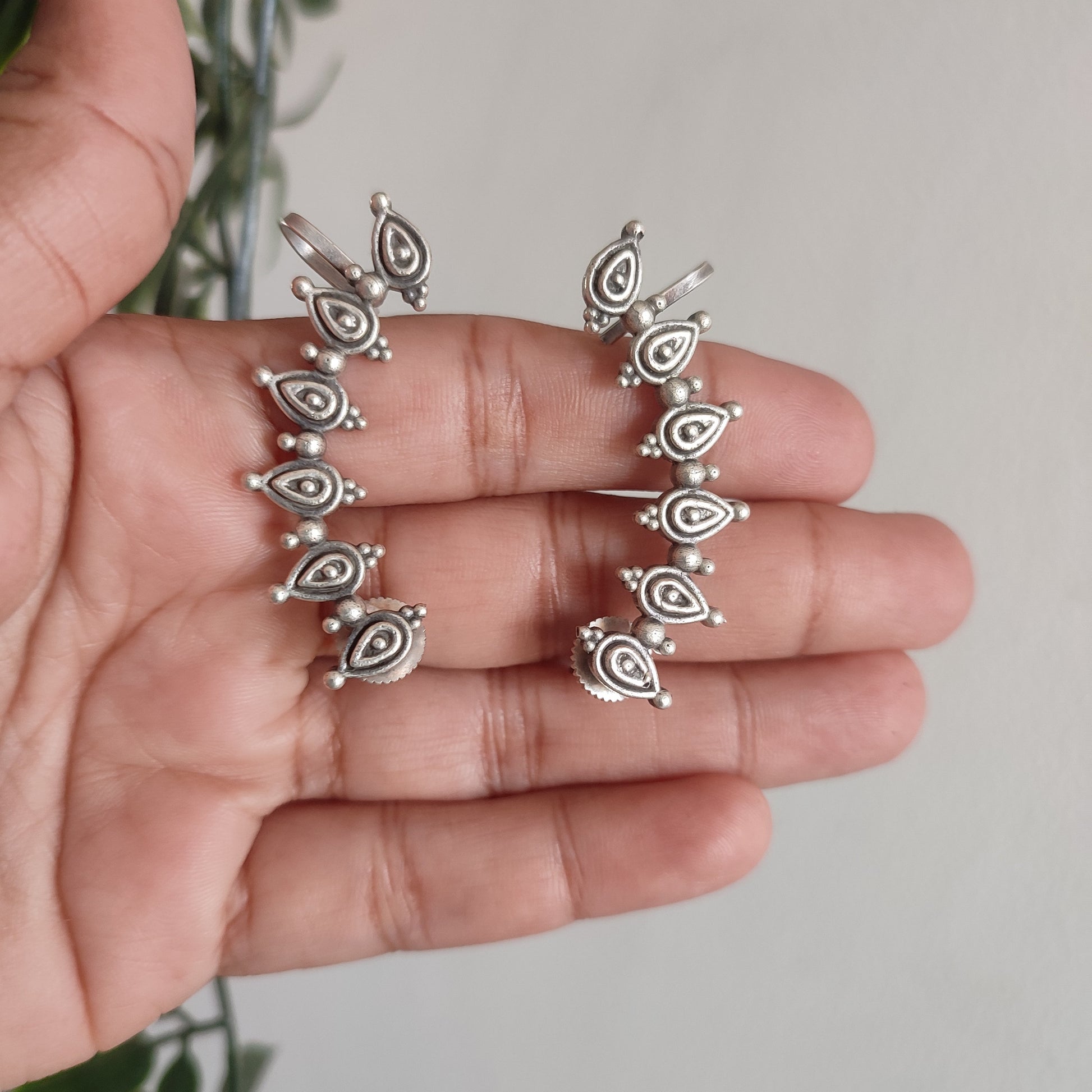 Silver rings on a hand with a blurred green plant background