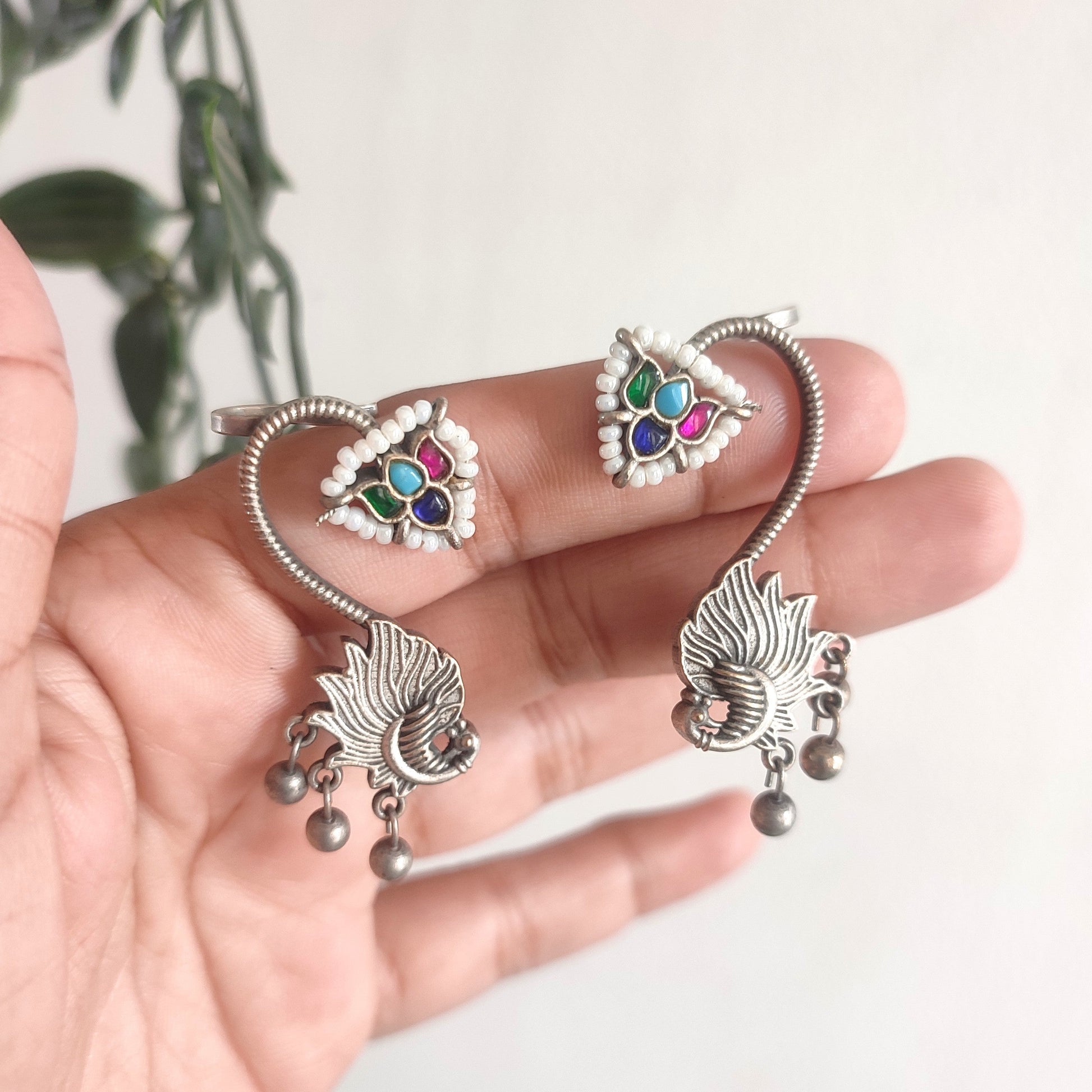 Silver jewelry set with colorful stones held in a hand against a light background