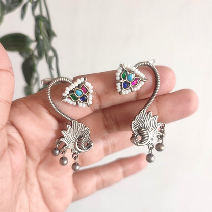 Silver jewelry set with colorful stones held in a hand against a light background
